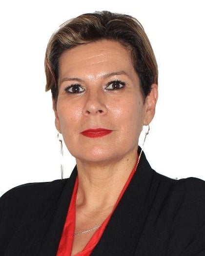 Retrato de Mariela Matthies, con saco negro y blusa roja, de brazos cruzados.